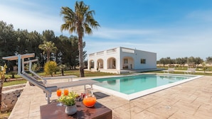 A poolside area with a white building, a clear blue sky, and a palm tree. - Beautiful private villa for 6 people with WIFI, private pool, A/C and TV, close to Brindisi (San Vito Dei Normanni)
