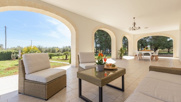 A spacious patio with wicker furniture, a glass-top table, and a dining area with a chandelier. - Beautiful private villa for 6 people with WIFI, private pool, A/C and TV, close to Brindisi (San Vito Dei Normanni)