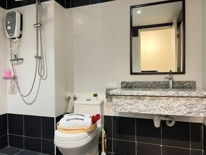 A bathroom with a toilet, a shower, a sink, and a mirror. - Tiara Desaru By Antlerzone (Bandar Penawar)