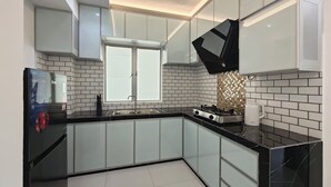 Une cuisine moderne avec des armoires blanches, des plans de travail noirs et un pare-feu en carrelage.