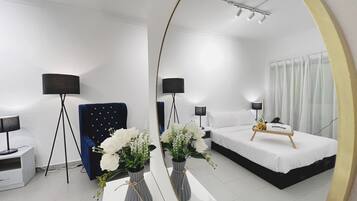 Une chambre d’hôtel moderne, dotée d’un grand miroir, d’un lit, de tables de chevet, d’un bureau et d’une chaise.