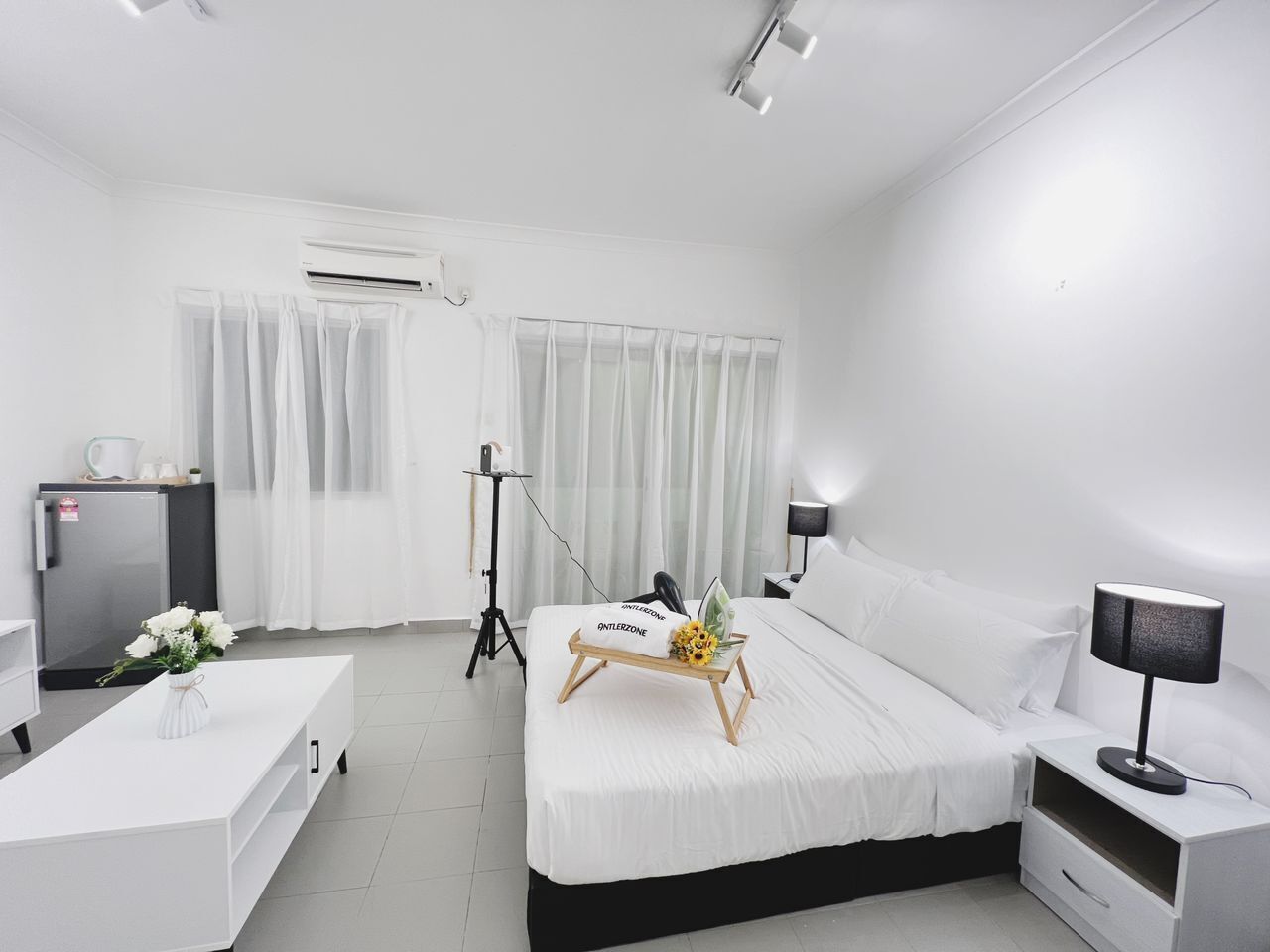 Ein modernes Hotelzimmer mit Bett, Nachttischen, einem Schreibtisch, einer Klimaanlage und einem fenster mit Vorhängen.