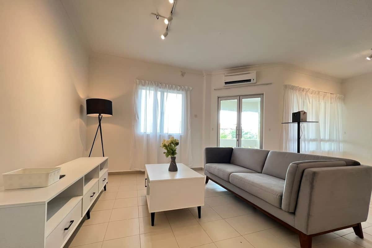Un salon moderne comprenant un canapé, une table basse, un meuble pour la télévision et une lampe.