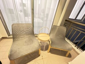 Un balcon avec deux fauteuils gris à revêtement rembourré et une petite table ronde.
