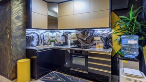 A modern kitchen with black and gold cabinetry, a marble backsplash, and a built-in oven. - Xspa Apartment Cryptocurrency pay Available (Novi Sad)