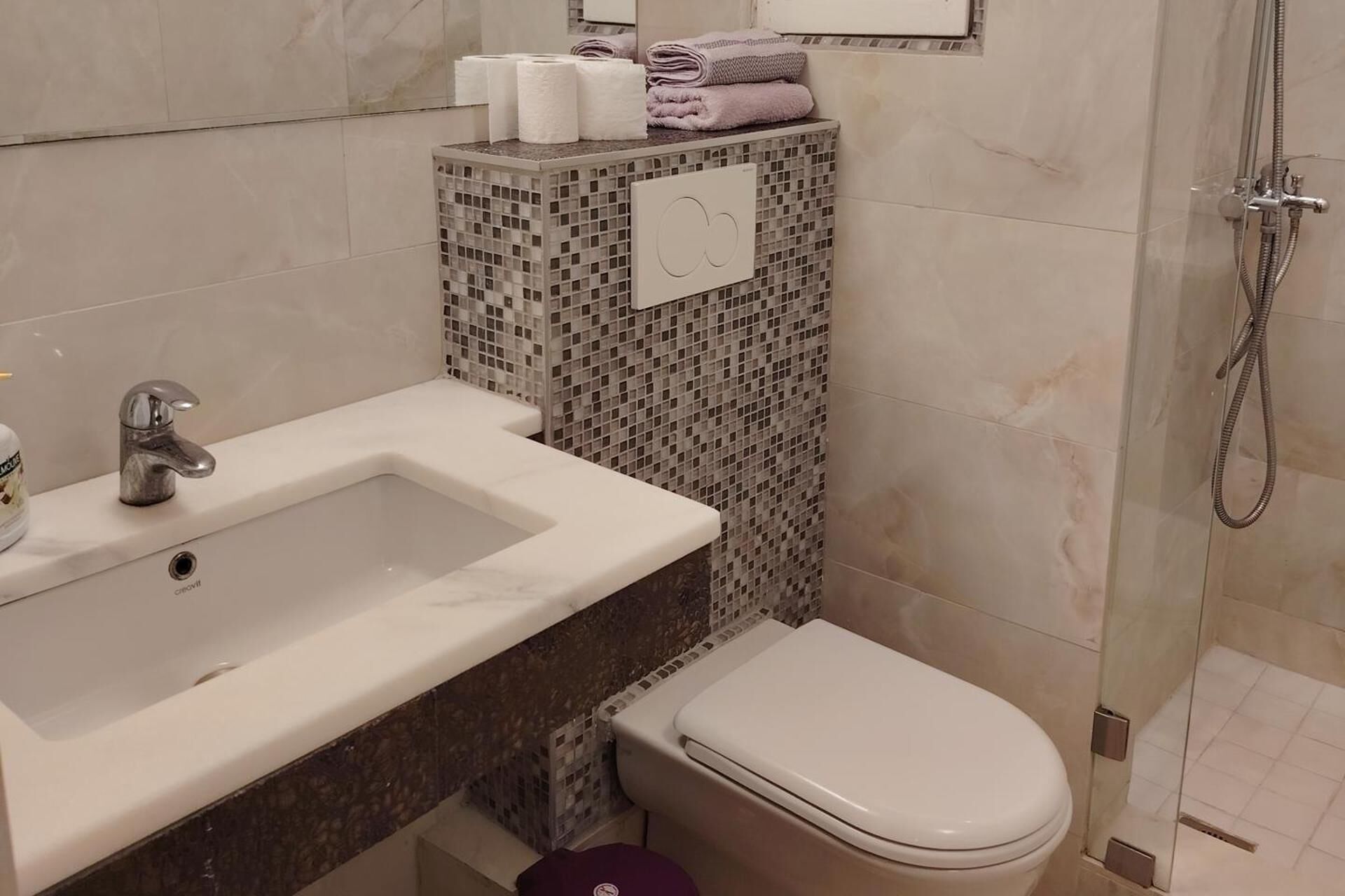 Une salle de bain avec un lavabo blanc, des toilettes et une douche.