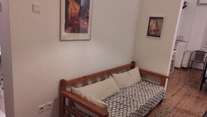 Una habitación con una cama de madera, una colcha estampada y dos cuadros en la pared.