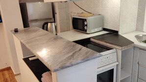 Una cocina compacta con estufa integrada, microondas y una pequeña encimera.