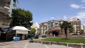 Un patio con un quiosco, un banco de piedra y una palmera.