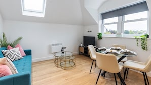 Un salon moderne avec un canapé bleu, une table basse en verre et un coin repas comprenant une table ronde et des chaises.