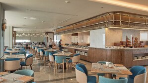 En moderne restaurant med et centralt barområde, flere spiseborde og stole.