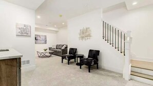 Un interior moderno con una escalera, un conjunto de sofás y una mesa de centro.
