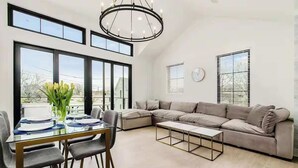Una sala de estar moderna con un sofá modular, una mesa de comedor de vidrio y una araña.