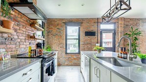 Una cocina moderna con paredes de ladrillo, una ventana, electrodomésticos de acero inoxidable y un lavamanos.