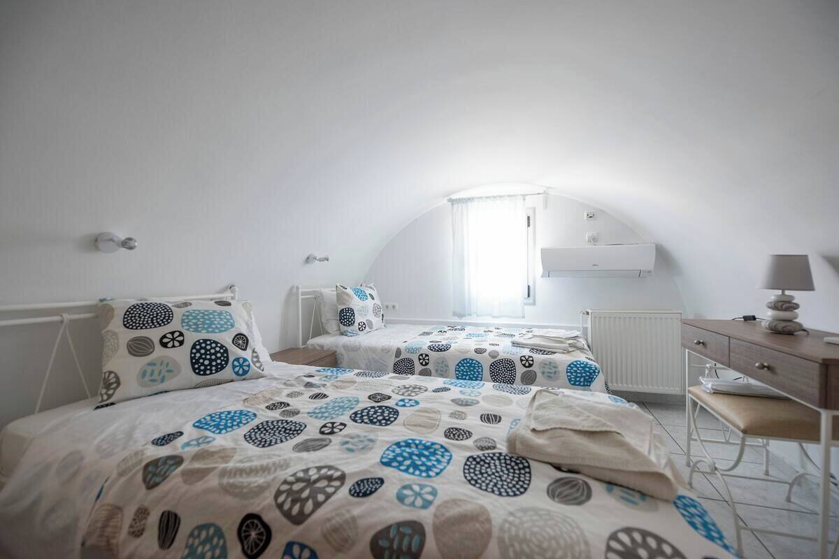 A bedroom with two beds, a desk, and a radiator.