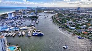Un port de plaisance où sont amarrés de nombreux bateaux, un grand bâtiment d’hôtel et un quartier résidentiel avec des maisons le long du front de mer.