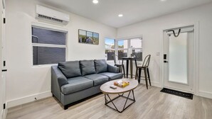 Un salon moderne avec un canapé gris, une table basse et un coin repas comprenant deux chaises.