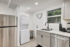 A modern kitchen with stainless steel appliances, a built-in dishwasher, and a window with a view of greenery.
