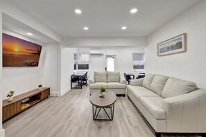 Un salon moderne avec un canapé beige, une table basse et un téléviseur fixé au mur.