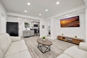 Un salon moderne avec un canapé, une table basse et une cuisine en arrière-plan.