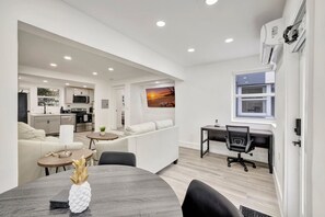 Een modern appartement met een keuken, eetgedeelte en woonkamer met een bank en bureau.