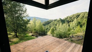 A wooden deck with a view of a forested valley and mountains. - PurpleVague (Runcu)