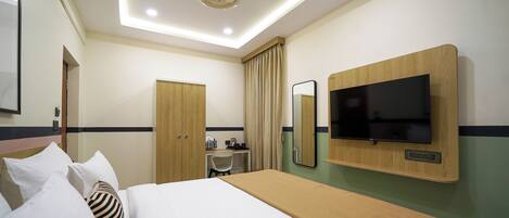 Una habitación de hotel con cama, escritorio, silla, televisor y armario.