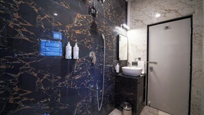 Un bagno moderno con una parete in marmo nero, un lavandino bianco e una doccia.