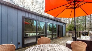 Una terraza con mobiliario de mimbre y una mesa, con vista a un edificio con grandes ventanales.