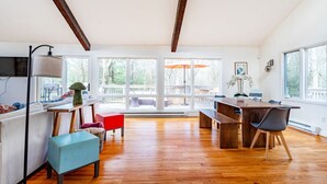 Una habitación amplia con suelos de madera, una mesa de comedor con sillas, un sofá y una silla roja.