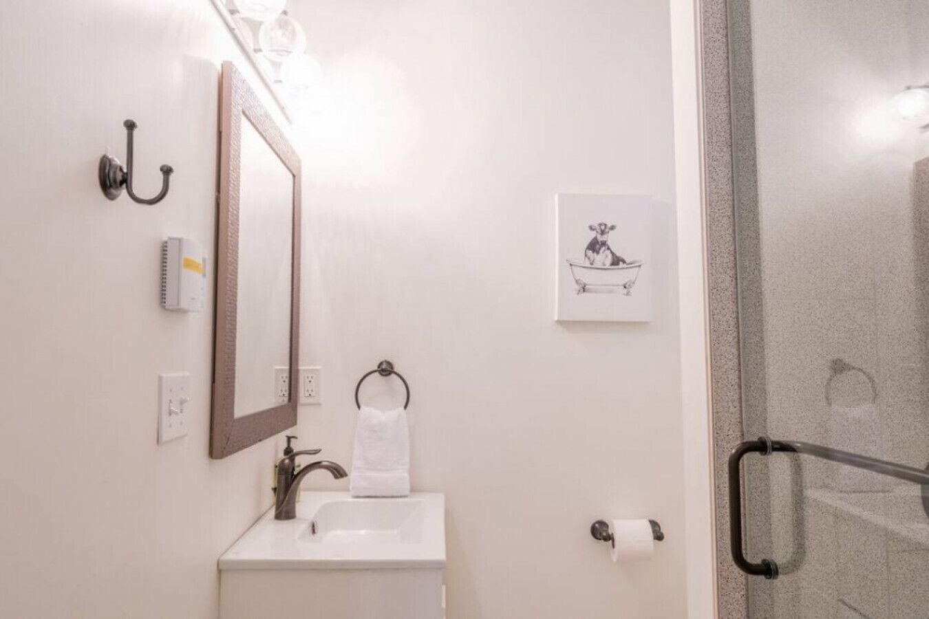 A bathroom with a sink, mirror, towel rack, and a framed picture on the wall.