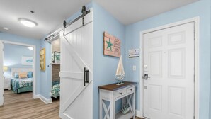 A room with a sliding barn door, a small table with a sailboat model, and a door with a decorative panel.