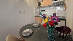 Una cocina pequeña con una mesa de comedor, un florero con flores y un microondas.