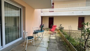 Un balcón con una mesa, sillas y una butaca roja.