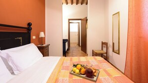 Ein Hotelzimmer mit einem Bett, einem Obstteller und einem Getränk, einem Nachttisch und einem Sessel.