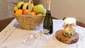 Ein Tisch mit einem Korbwägelchen, das Früchte, eine Weinflasche, Weingläser und ein dekorativer Krug enthält.