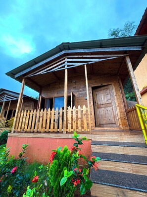 Une cabane en bois avec une véranda, une clôture en bois et une porte.