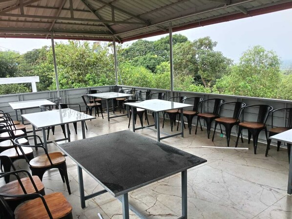 An outdoor patio area with tables and chairs, surrounded by greenery. - Hill View Paradise (Gokarna)