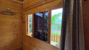 Una habitación de cabaña de madera con ventana, cortina y suelo de madera.