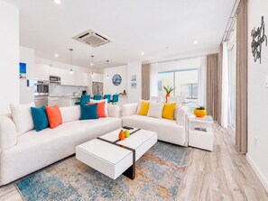 A modern living room with a sectional sofa, a coffee table, and a dining area with chairs.