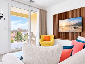A modern living room with a sofa, a yellow armchair, and a television mounted on a wooden panel wall.