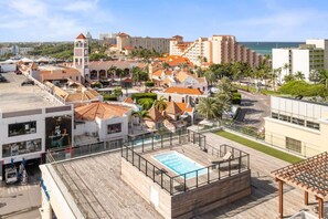 Uma área de piscina no terraço, com vista para o oceano e edifícios ao redor.