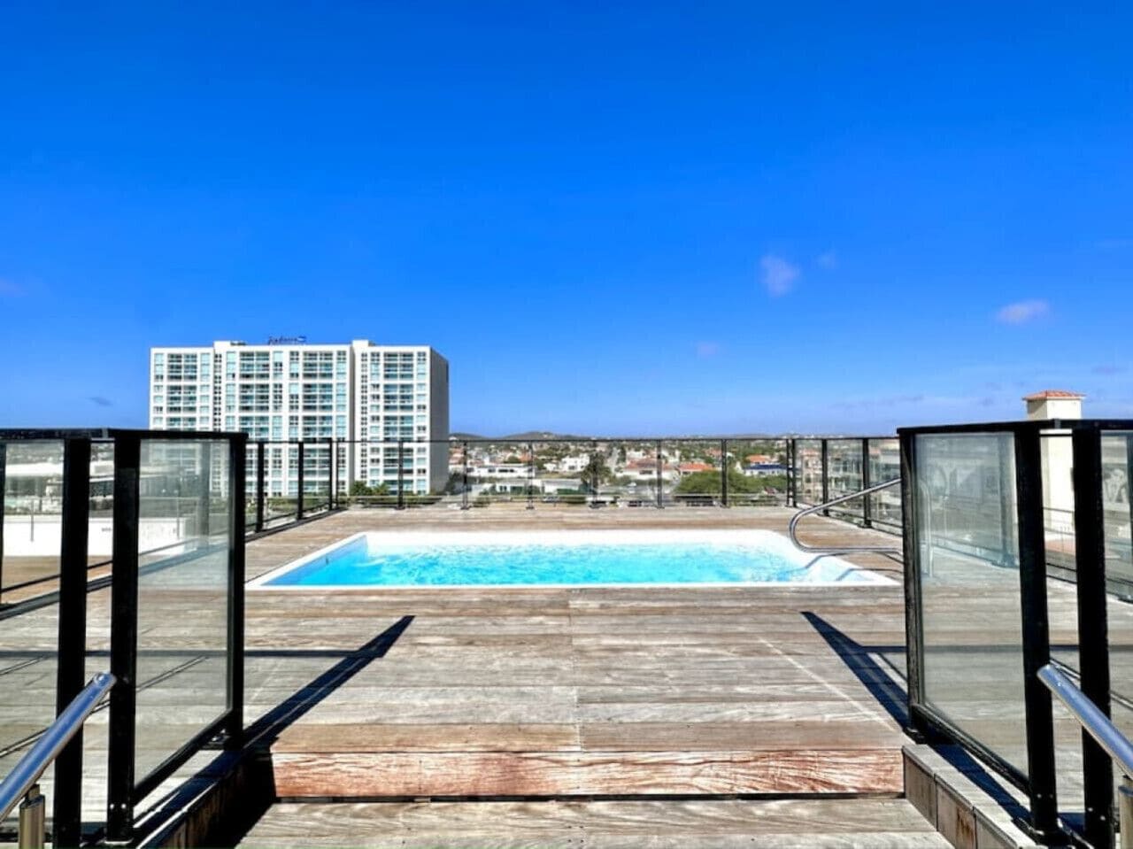 Una piscina en la azotea con vistas despejadas a un rascacielos al fondo.