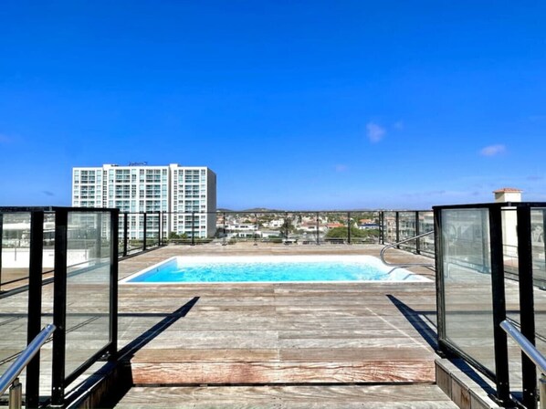 Una piscina en la azotea con vistas despejadas a un rascacielos al fondo.