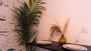 A kitchen with a wooden countertop, two stools, a potted plant, and a vase with dried plants. - Charming Bright Duplex (Angers)