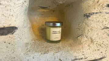 A candle labeled 'BERGAMOT AMBERWOOD' in a stone crevice.