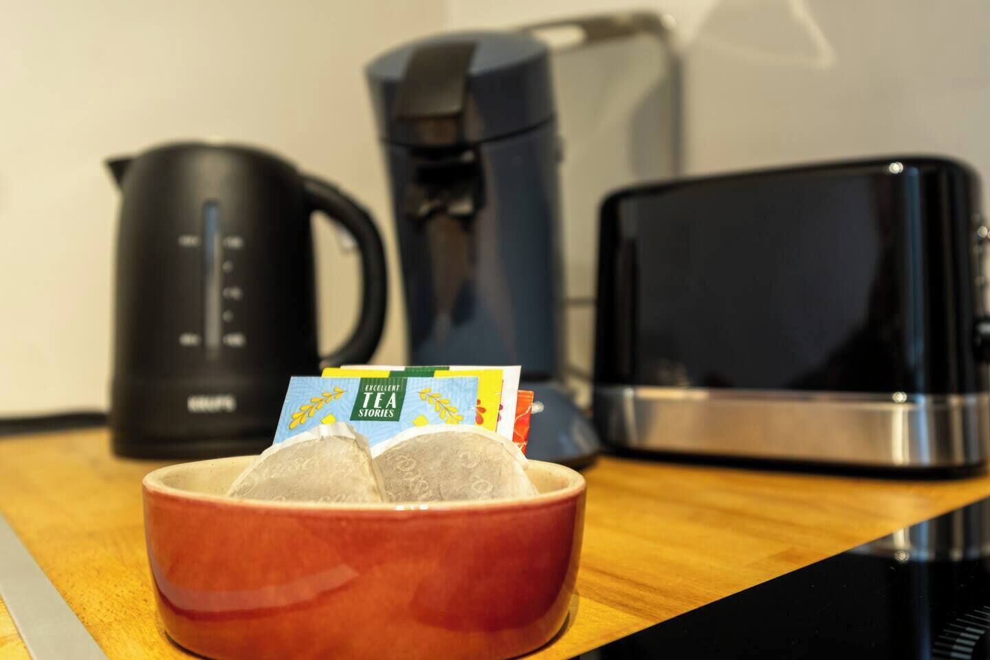 A kitchen counter with a coffee maker, a kettle, and a microwave.