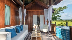 A wooden cabin with a glass-top table, white sofa, and a hot tub.