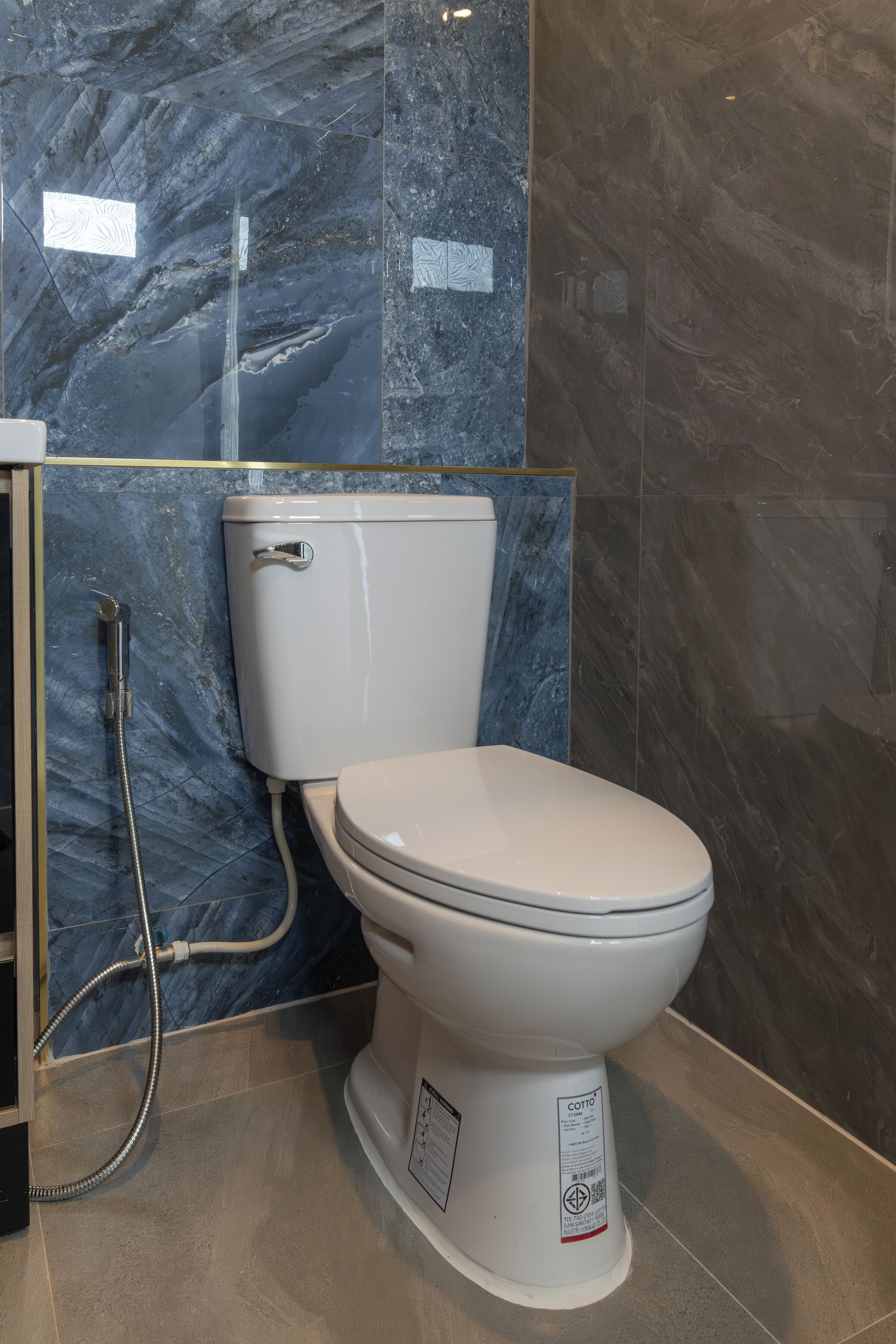 A modern bathroom with a toilet, shower, and marble walls.