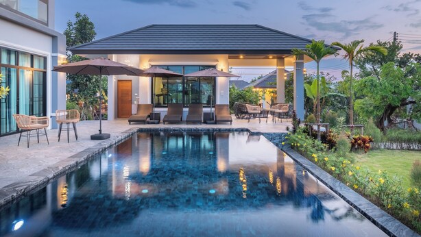 A modern house with a swimming pool, outdoor seating, and a covered patio area.